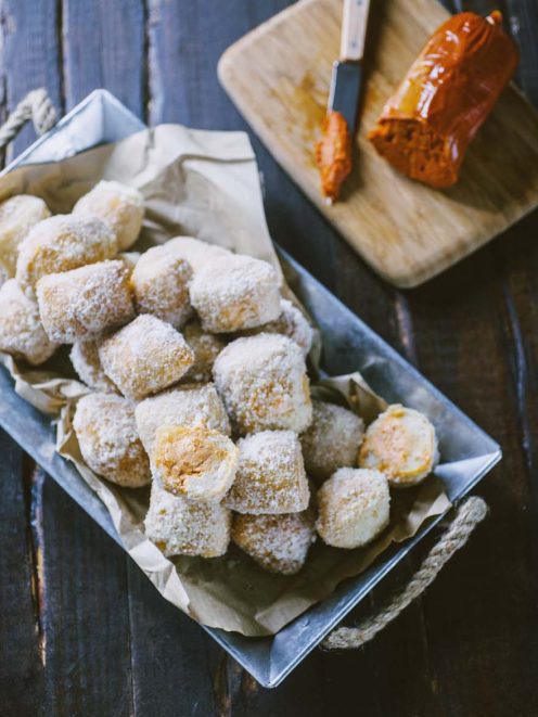 Pasta lievitata fritta spolverata di zucchero a velo, servita in abbondanza con uno spaccato che rivela il ripieno dorato