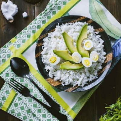 Riso al cocco servito con fette di avocado e uova sode a metà
