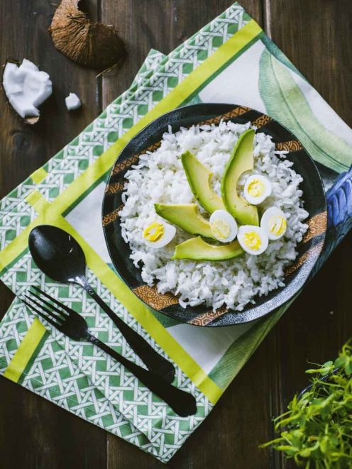 Riso al cocco servito con fette di avocado e uova sode a metà