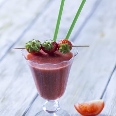 Smoothie di fragola, pomodoro e zenzero guarnito con fragoline su spiedino e cannucce verdi