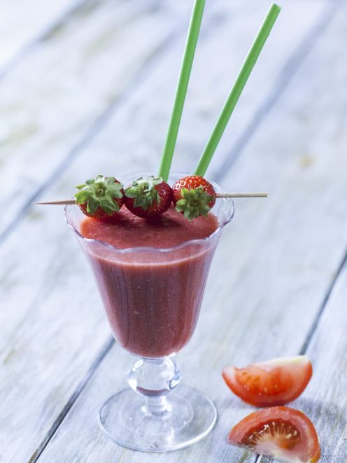 Smoothie di fragola, pomodoro e zenzero guarnito con fragoline su spiedino e cannucce verdi