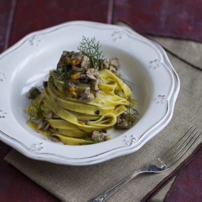 Tagliatelle senza glutine al ragù di coniglio arrotolate nel piatto e guarnite con finocchietto selvatico