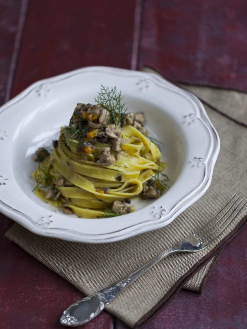Tagliatelle senza glutine al ragù di coniglio arrotolate nel piatto e guarnite con finocchietto selvatico