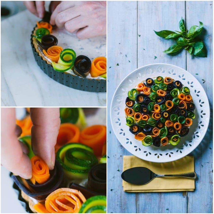 Mani che dispongono roselline di zucchine e carote sulla torta salata prima di servirla
