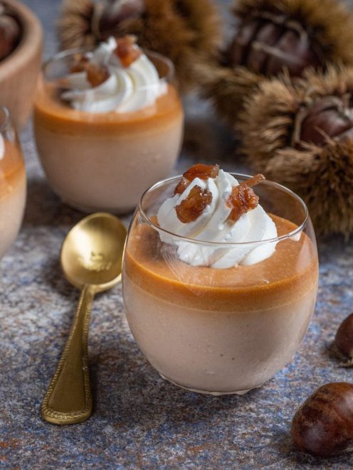 Panna cotta alle castagne in bicchiere, con strato di caramello e ciuffo di panna montata guarnito di castagne caramellate