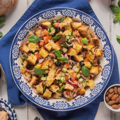 Panzanella croccante con crostoni di pane, pomodoro, cetriolo, olive nere, cipolla rossa e foglie di basilico