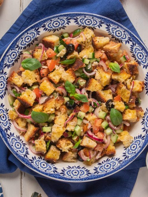 Panzanella croccante con crostoni di pane, pomodoro, cetriolo, olive nere, cipolla rossa e foglie di basilico