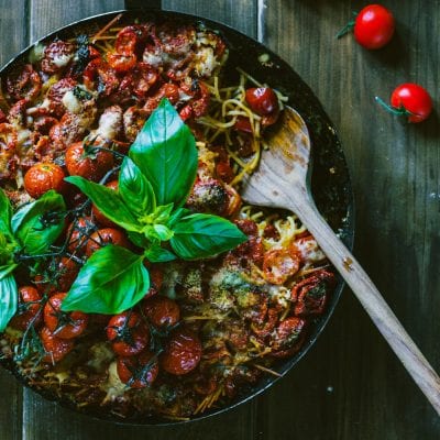 Spaghetti arraganati con pomodorini arrosto, formaggio grattugiato e basilico fresco