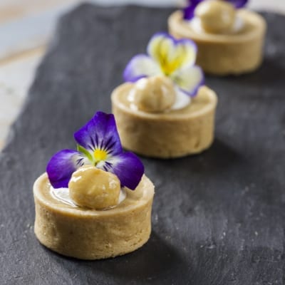 Tartellette allo yuzu con crema, nocciola glassata e fiori di viola eduli