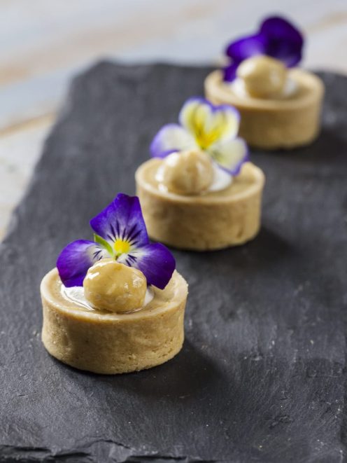 Tartellette allo yuzu con crema, nocciola glassata e fiori di viola eduli