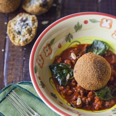 Arancini di couscous con sarde adagiati su ragù di pomodoro con foglie di basilico fritto