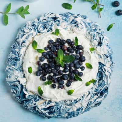 Blueberry Pavlova con meringa marmorizzata, panna montata, mirtilli freschi e foglioline di menta