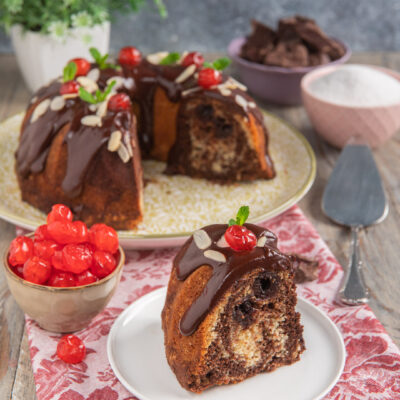 Ciambella onde del Danubio glassata al cioccolato con lamelle di mandorle e ciliegie candite, servita a fette
