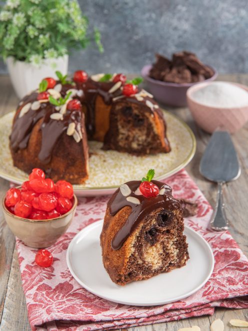Ciambella onde del Danubio glassata al cioccolato con lamelle di mandorle e ciliegie candite, servita a fette