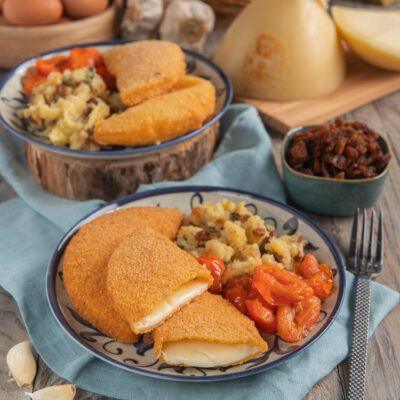 Cotoletta di caciocavallo impanata e fritta, con filante interno a vista, servita con patate e pomodorini