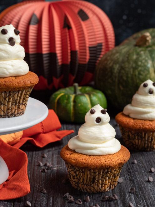 Cupcake di zucca decorati con frosting a forma di fantasma e gocce di cioccolato per Halloween