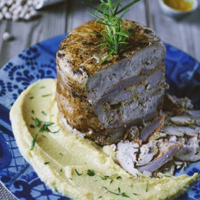 Kebab arrosto su letto di hummus cremoso, guarnito con un rametto di rosmarino fresco