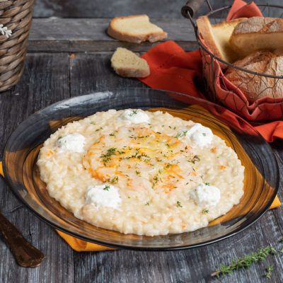 Risotto con crudo di gamberi mantecato, guarnito con quenelle di formaggio fresco e timo