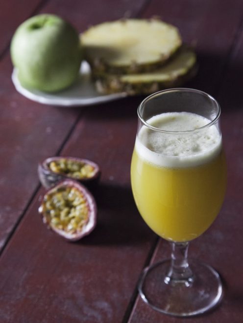 Succo di ananas, mela verde e passion fruit con schiuma in calice, affiancato da frutta fresca tagliata