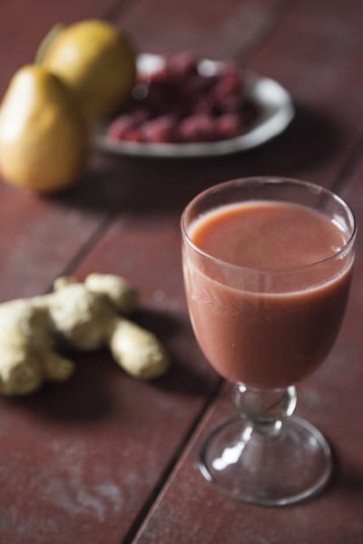 Succo di pera, lamponi e zenzero servito con radice di zenzero fresca e lamponi sullo sfondo