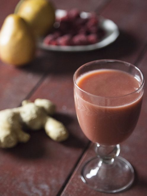 Succo di pera, lamponi e zenzero servito con radice di zenzero fresca e lamponi sullo sfondo