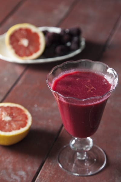 Succo di pompelmo rosa, ribes e more servito in calice con mezzi pompelmi accanto