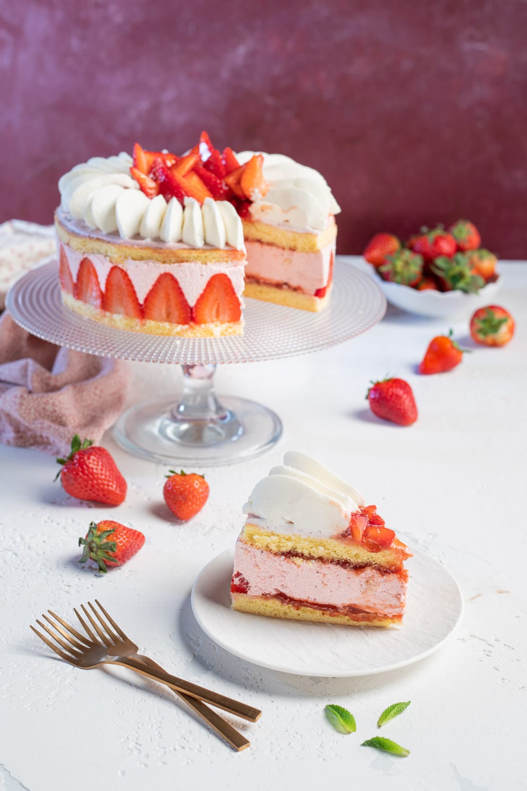 Fetta di torta con mousse di fragole tra due strati di pan di spagna e ciuffi di panna