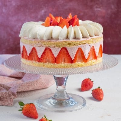 Torta con mousse di fragole con pan di spagna, crema alla fragola e fragole fresche a spicchi