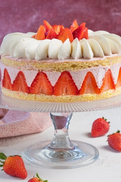 Torta con mousse di fragole con pan di spagna, crema alla fragola e fragole fresche a spicchi
