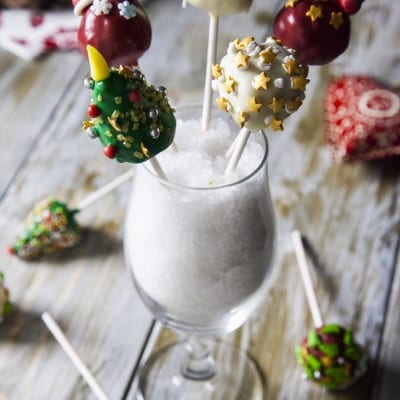 Cake pops natalizi decorati con stelle dorate, alberi di Natale verdi e palline rosse su stecco