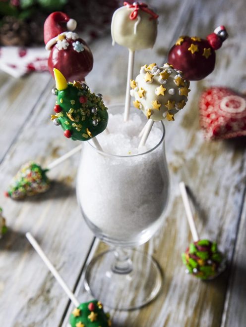 Cake pops natalizi decorati con stelle dorate, alberi di Natale verdi e palline rosse su stecco