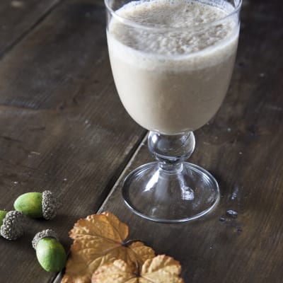 Smoothie di banana, carruba e latte di nocciole servito in calice con superficie schiumosa