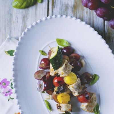 Souvlaki di pesce spada con zucchine, pomodorini e uva, guarnito con foglie di basilico