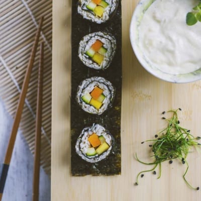 Sushi di verdure con carota, zucchina e mango avvolti in alga nori, serviti con salsa cremosa