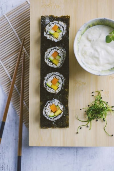 Sushi di verdure con carota, zucchina e mango avvolti in alga nori, serviti con salsa cremosa