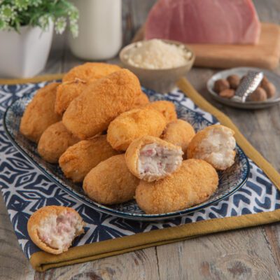 Crocchette di latte dorate e croccanti, una spezzata rivela il ripieno cremoso con prosciutto