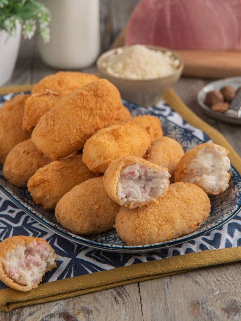 Crocchette di latte dorate e croccanti, una spezzata rivela il ripieno cremoso con prosciutto