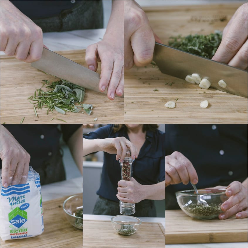 Erbe aromatiche e aglio tritati sul tagliere, poi mescolati con sale e pepe in una ciotola