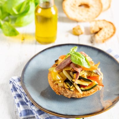 Frisella con caponata di verdure, zucchine, peperoni e foglia di basilico fresco