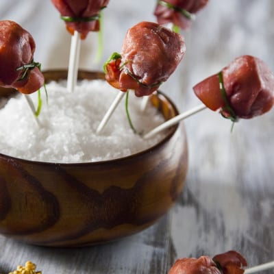 Lollipop di bresaola con caprino e noci su stecchi, serviti su sale grosso