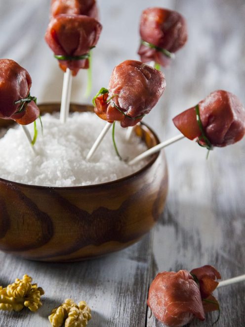 Lollipop di bresaola con caprino e noci su stecchi, serviti su sale grosso