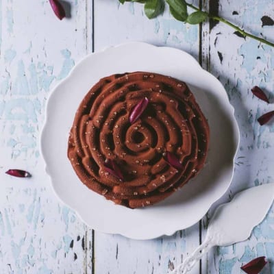 Rosa di mousse al cioccolato spolverata di cacao, decorata con petali di rosa e zucchero granulato