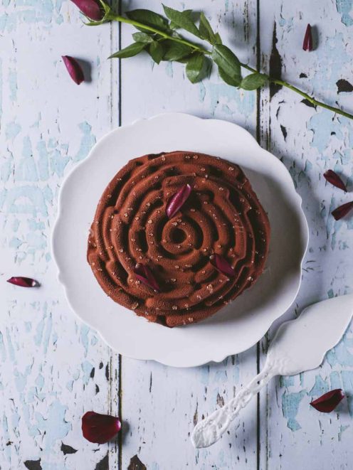 Rosa di mousse al cioccolato spolverata di cacao, decorata con petali di rosa e zucchero granulato