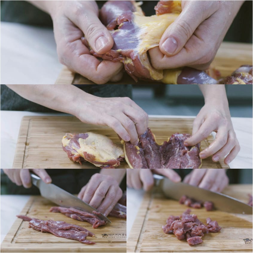 Mani che rimuovono la pelle dall'anatra e tagliano la carne a pezzetti sul tagliere