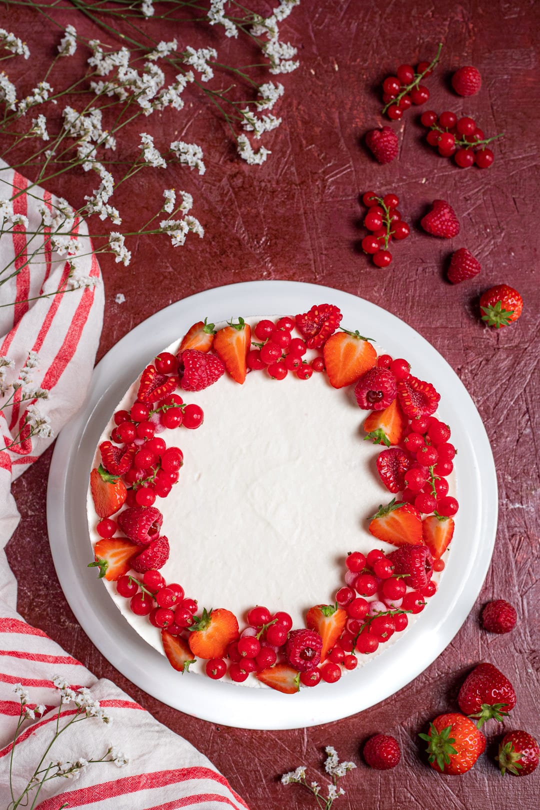 Torta fredda alla ricotta decorata con un bordo di fragole, lamponi e ribes rosso