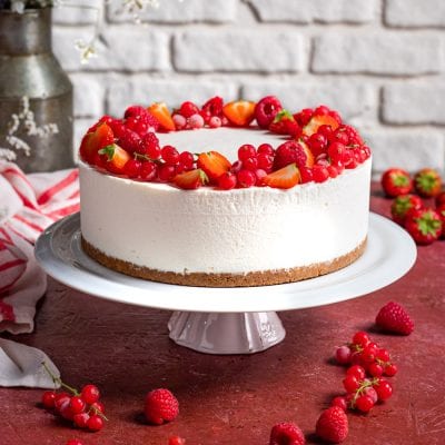 Torta fredda alla ricotta e frutti rossi con corona di fragole, lamponi e ribes sul bordo superiore