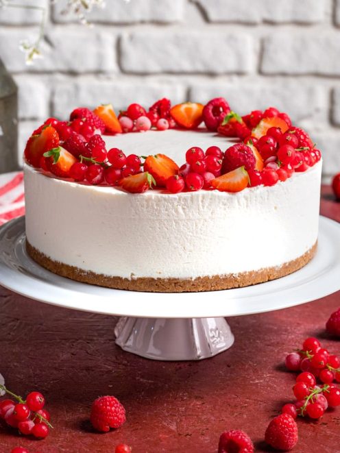 Torta fredda alla ricotta e frutti rossi con corona di fragole, lamponi e ribes sul bordo superiore