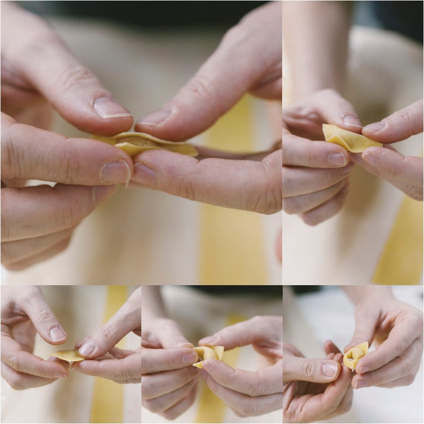 Mani che chiudono e formano un tortellino piegando la pasta fresca a triangolo
