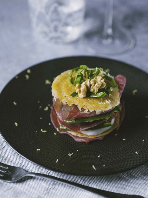 Millefoglie di bresaola a strati con mozzarella, rucola e noci, guarnita con scaglie di grana