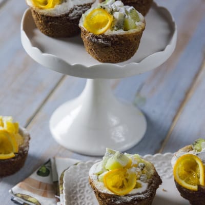 Mini cheesecake con frutta fresca, kiwi a cubetti e fettine di kumquat, spolverizzate di zucchero a velo